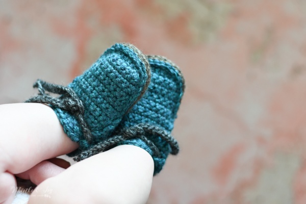 Chubby baby feet in blue crochet moccasins.