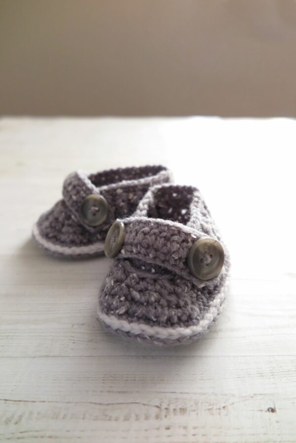 Grey crochet baby shoes with buttons.