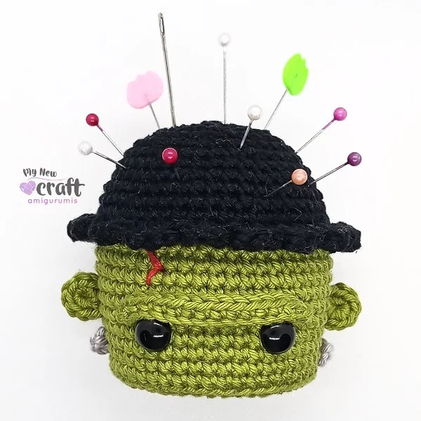 A crochet pin cushion with a Frankenstein theme.