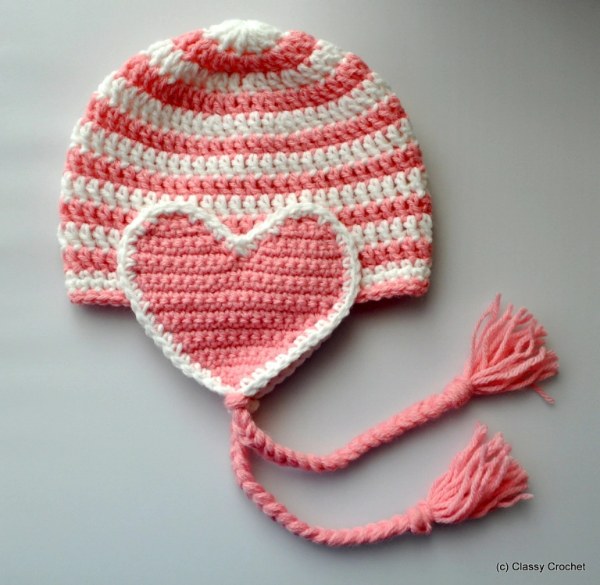 A flat lay image of a pink and white striped beanie with heart-shaped earflaps.