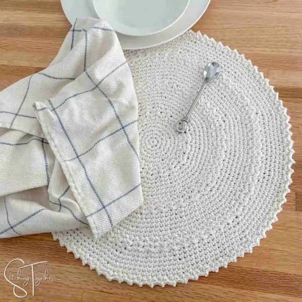 A single person table setting with a white crochet placemat.