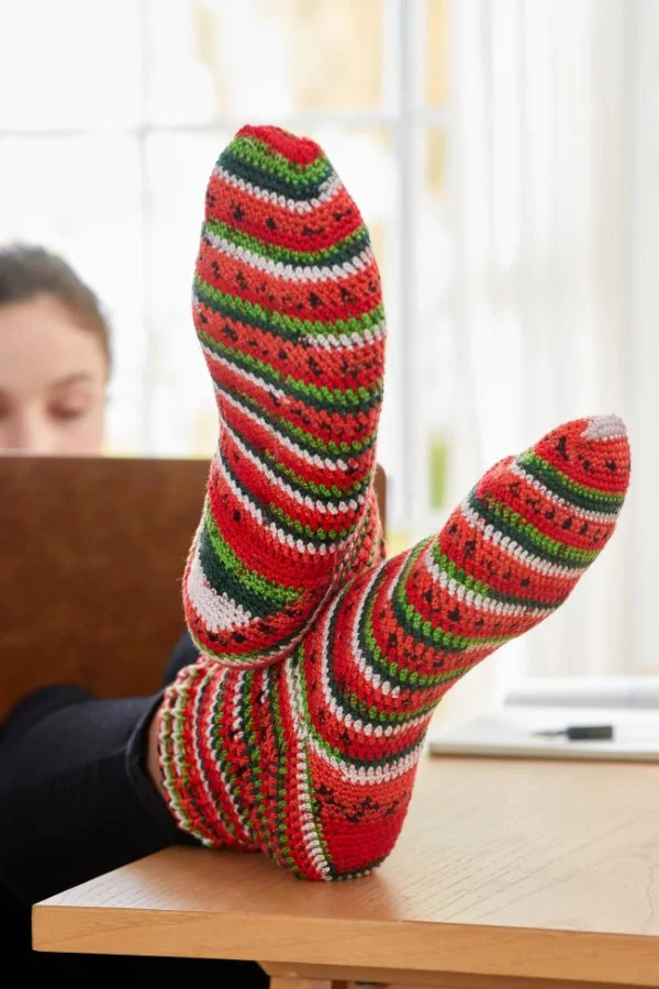 A closeup of crochet socks worked in a self-striping yarn.