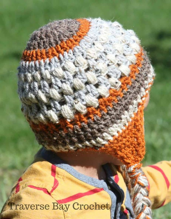 Back view of a toddler wearing a multicoloured crochet earflap beanie.