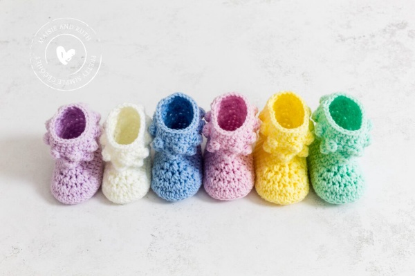 A row of crochet baby booties in different colours and sizes.