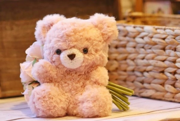 A closeup image of a fluffy crochet teddy bear made in faux fur yarn.