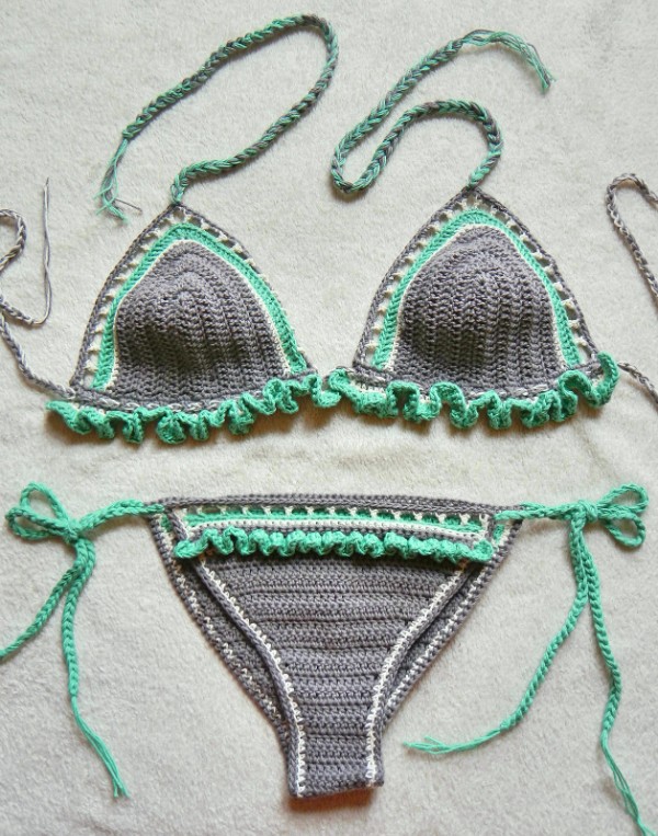 A flat lay image of a grey crochet bikini with green frills.