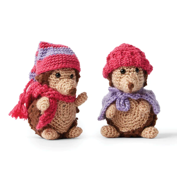 Two crochet hedgehog toys dressed in hats and scarves.