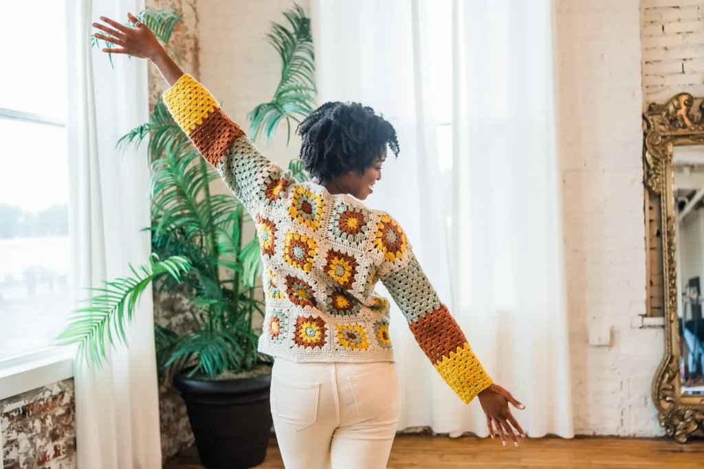 Back view of a woman wearing a crochet granny square pullover.
