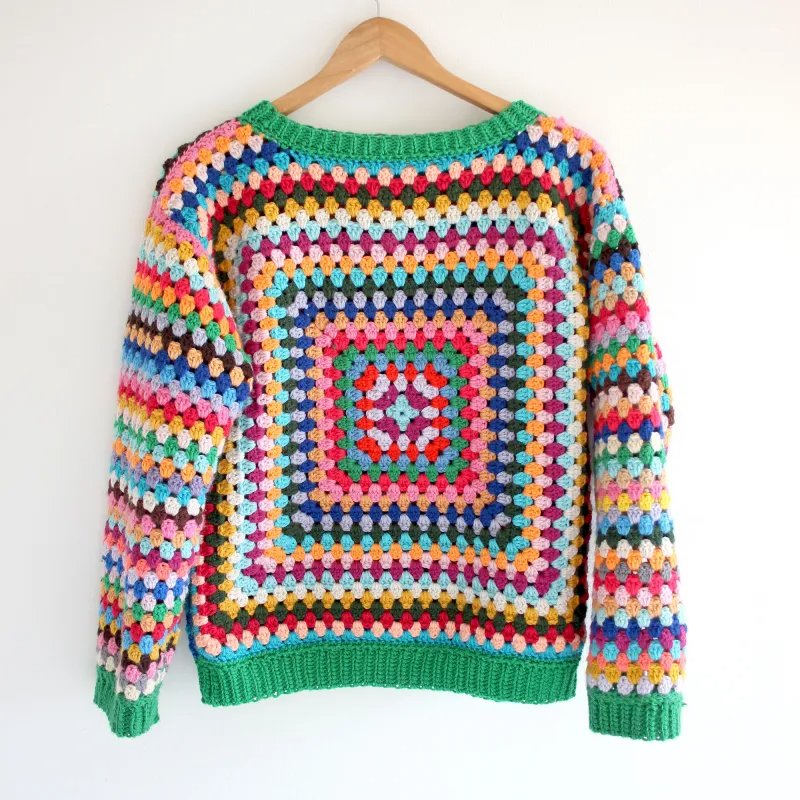 A crochet granny square sweater on a wooden hanger.