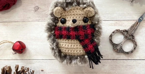 A crochet hedgehog wearing a plaid scarf.