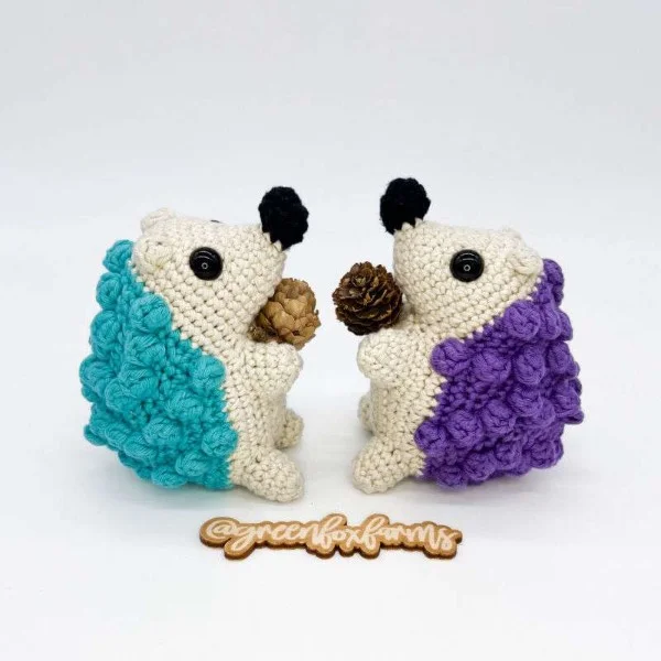 Two crochet hedgehog toys made in purple and blue yarn.
