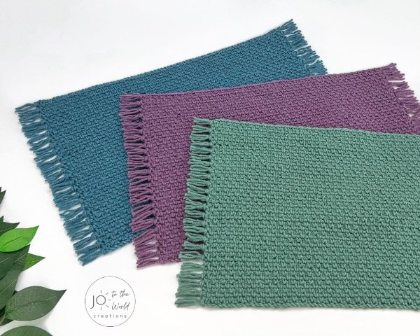 Three rectangular crochet placemats with fringing.