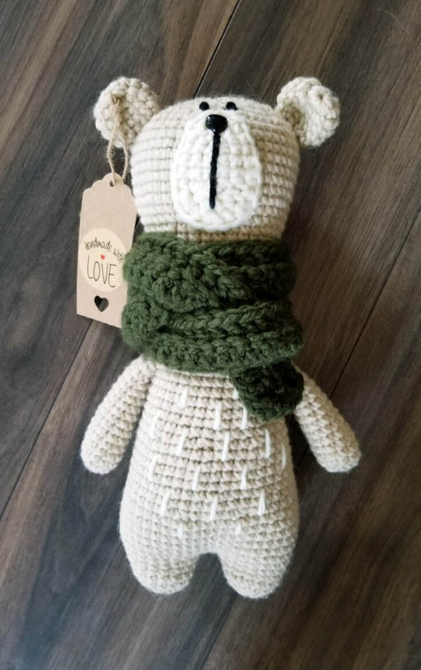 A long crochet bear with a forest green scarf.