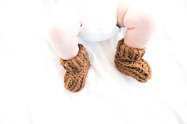 A closeup of a baby wearing crochet baby booties.