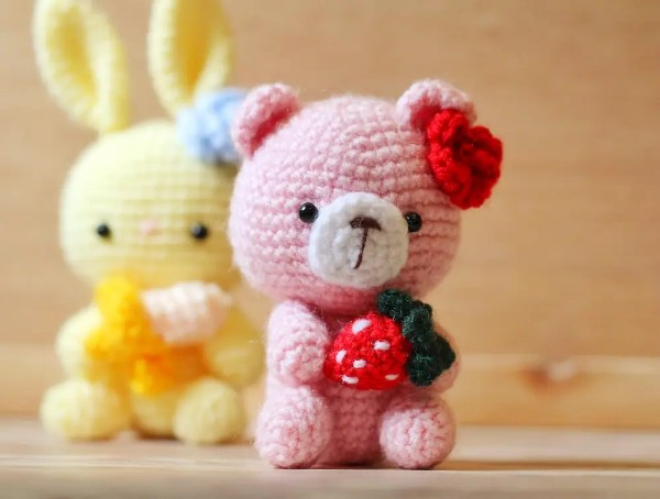A pink strawberry crochet bear toy.