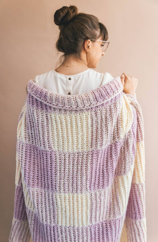A woman wearing a soft pink gingham crochet blanket over her shoulders.