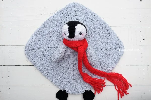 A fluffy grey penguin lovey with a red scarf.