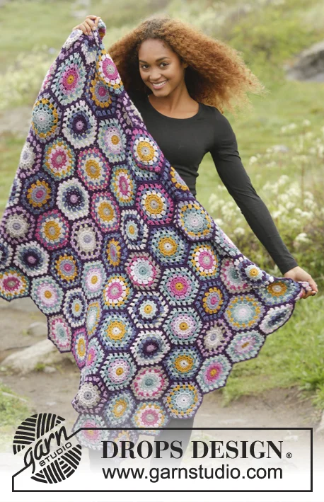 A woman holding a crochet blanket with a classic hexagon motif.