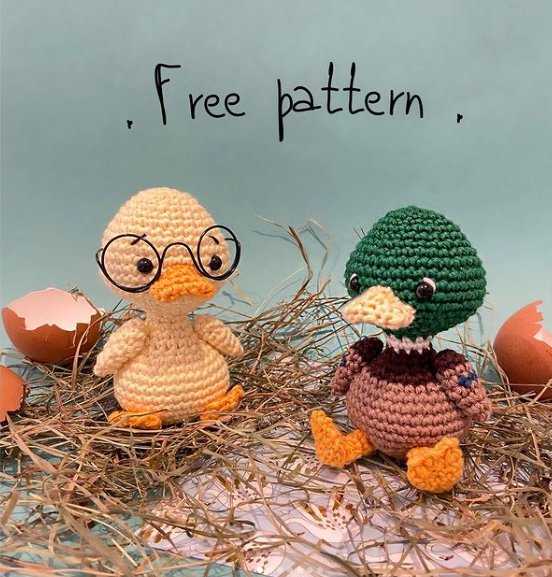 A yellow amigurumi duckling sitting next to an amigurumi mallard duck toy.