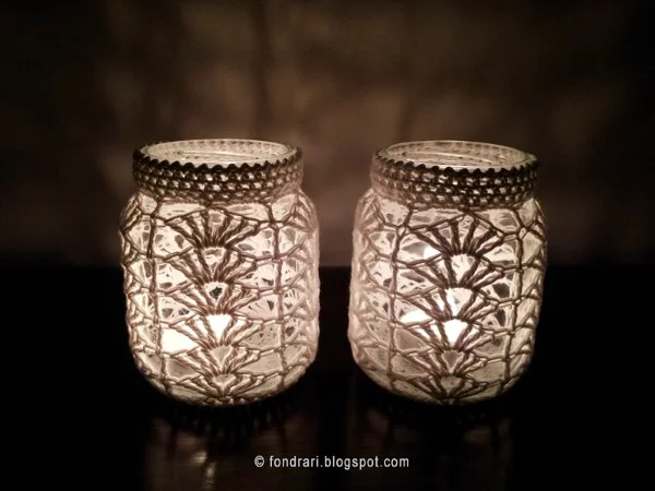 Two crochet covered jars with candles.