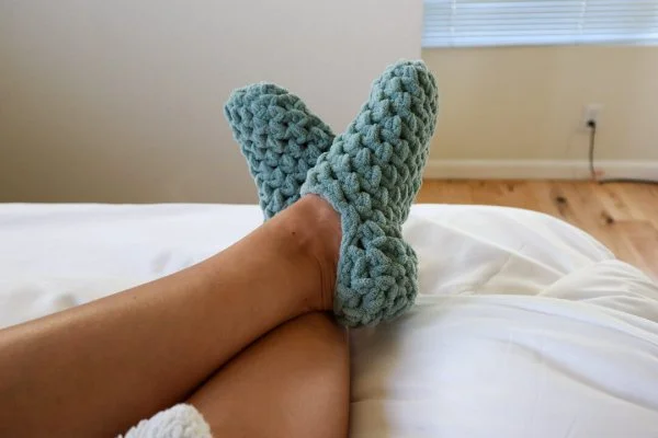 A close up of someone crossing there feet, wearing chunky blue slipper socks.