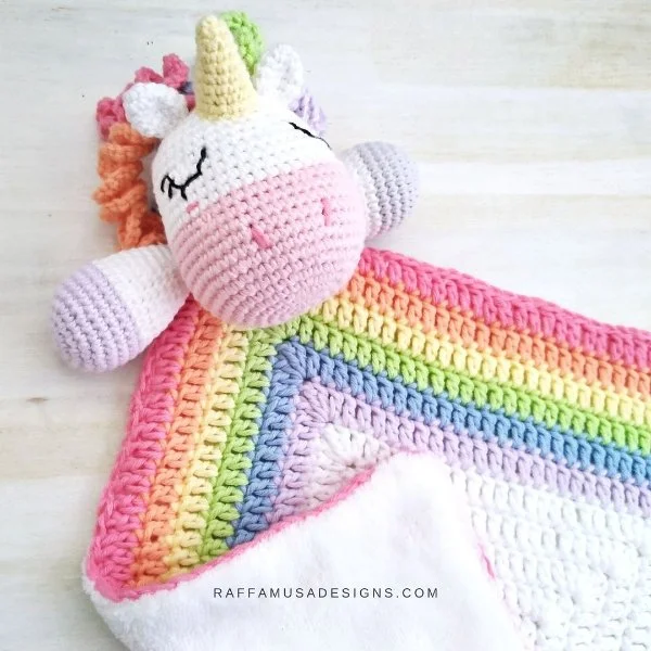 A rainbow coloured unicorn lovey with curly hair.