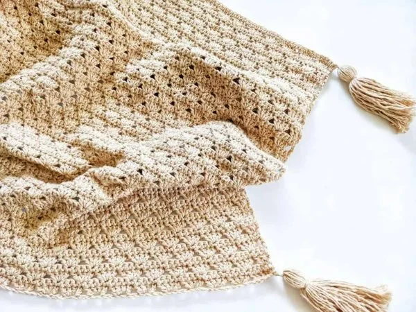 A shell stitch blanket with large tassels in the corners.