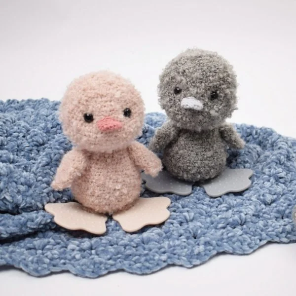 Grey and pink crochet ducks made in fluffy yarn.
