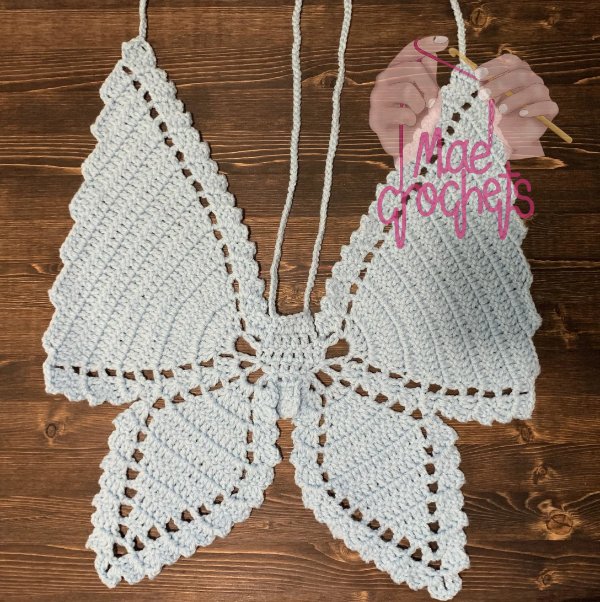 A flat lay image of an ivory coloured crochet butterfly top.