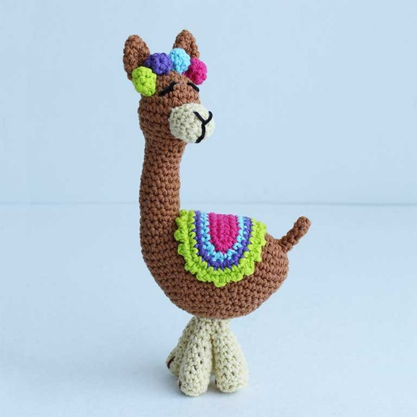 A tall crochet llama with a colourful saddle cloth and headpiece.