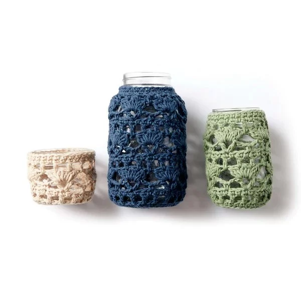 Three different sized mason jars with lacy crochet covers.
