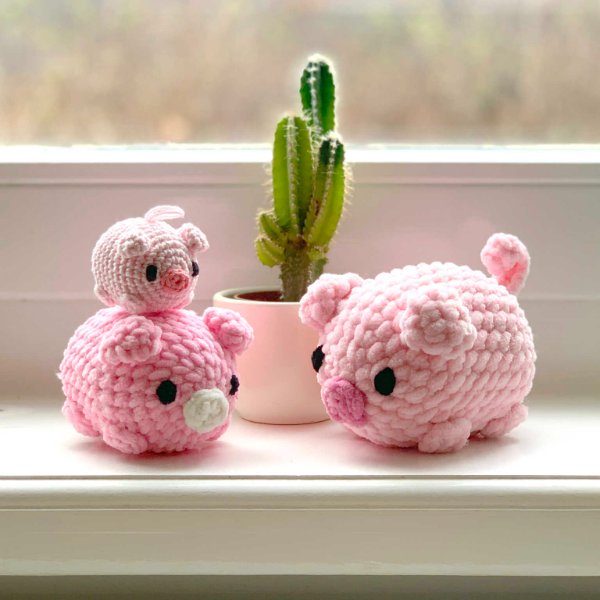 three little crochet pigs sitting on a window sill.