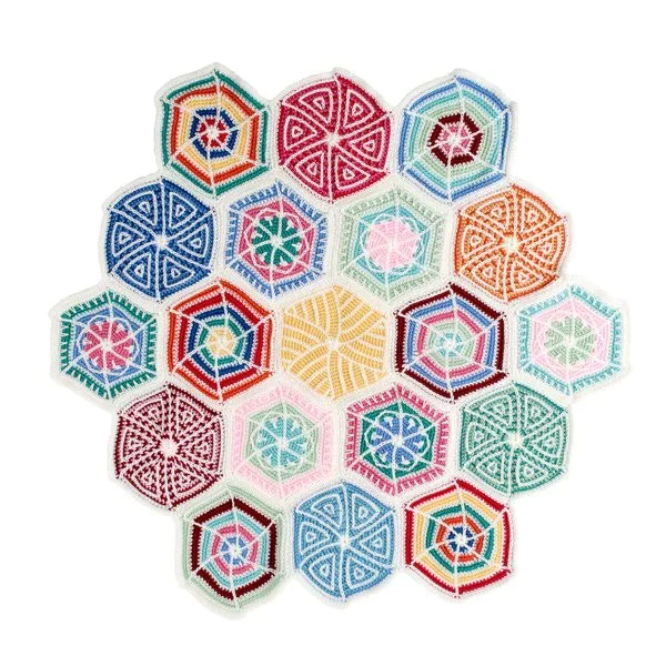 A flat lay image of a sampler-style crochet hexagon blanket.