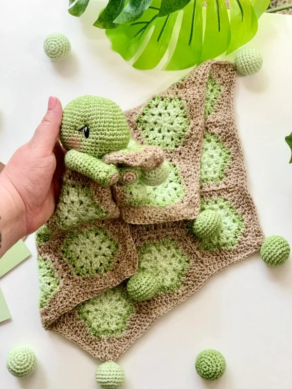 A green and brown crochet turtle baby lovey.