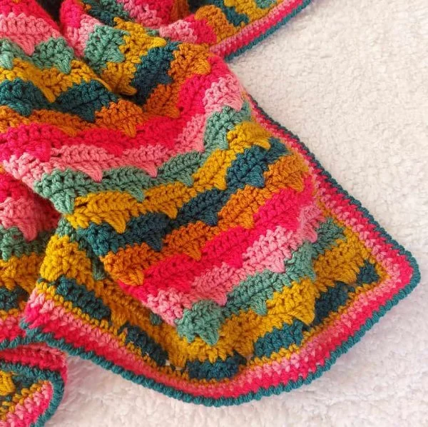 A brightly coloured scallop shell crochet baby blanket.