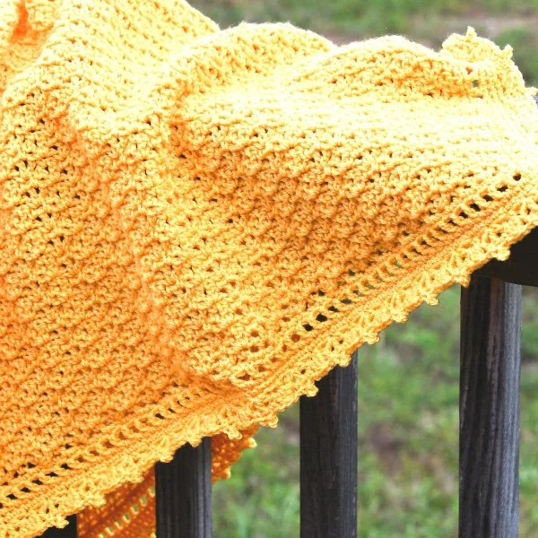 A yellow shell stitvch baby blanket iwth picot edging.