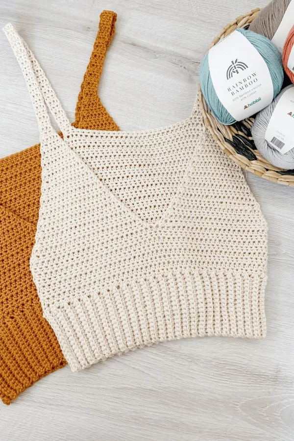 A flat lay image of two cropped-lenght,  v-neck crochet tank tops.