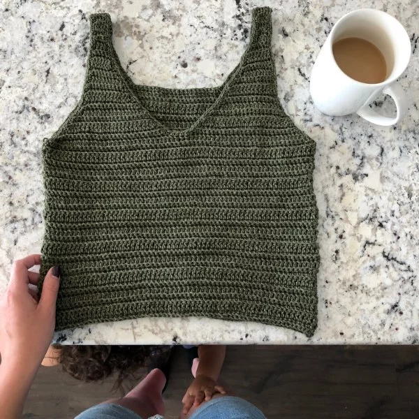 A flat lay image of a khaki green v-neck crochet top.