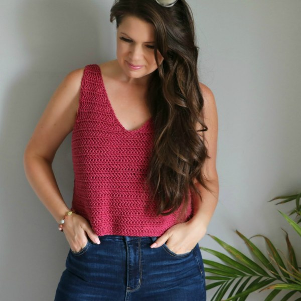 A woman wearing a simple, red crochet v-neck tank.