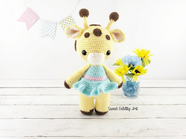 A standing crochet giraffe toy in a blue dress.