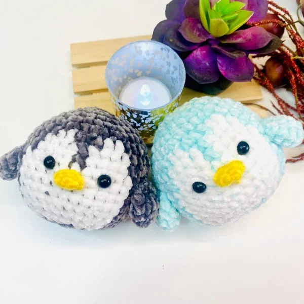 Two round crochet penguins in different colours.