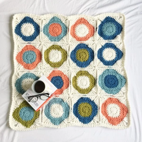 A modern geometric granny square blanket crocheted in bright colours.
