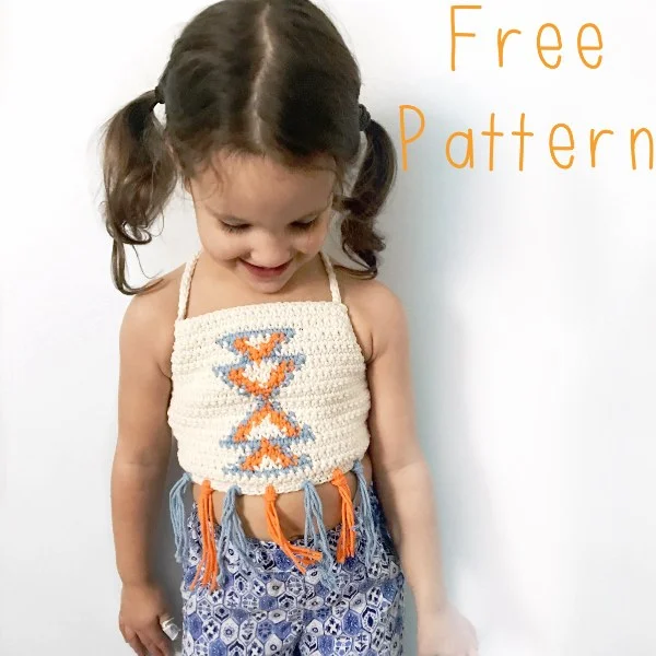 A little girl wearing a crochet top with an aztec-themed colourwork motif.