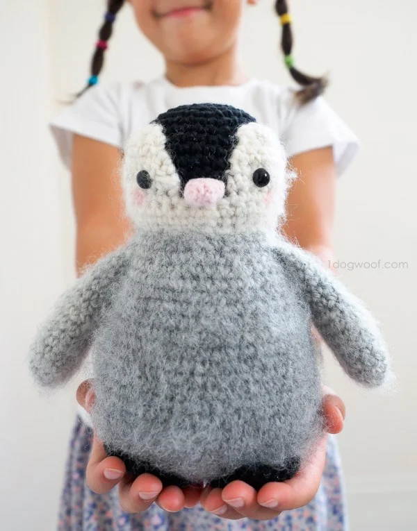 A child holding a chubby crochet penguin toy.