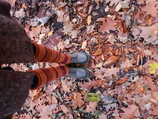 A top-down view of a persons legs in striped crochet leg warmers.