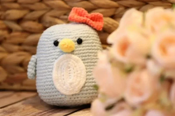 A chubby amigurumi penguin with a bow on it's head.