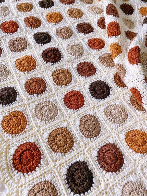 A circle-in-a-square granny square blanket crocheted in warm earthy colours.