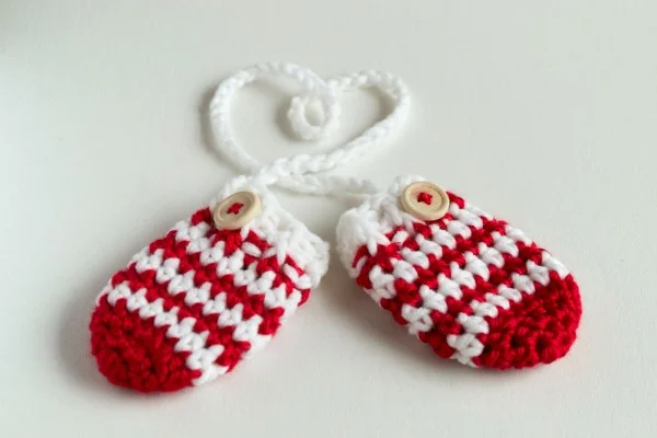 Red and white striped crochet baby mittens.