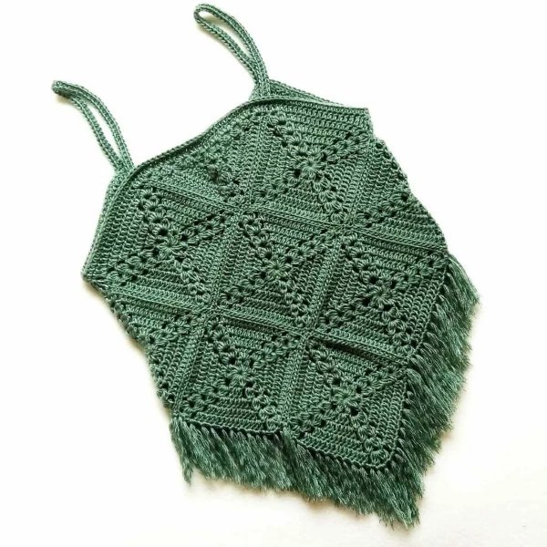 A flat lay image of a green crochet granny square top with fringing,