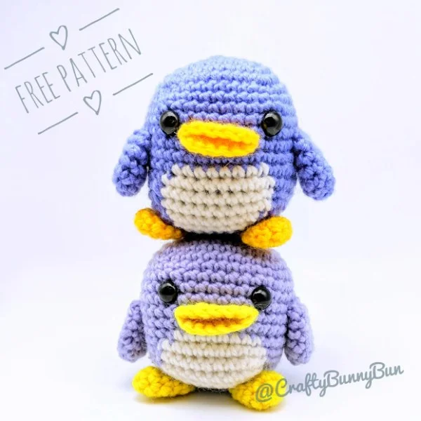 Two crochet penguin amigurumi stacked on top of each other.